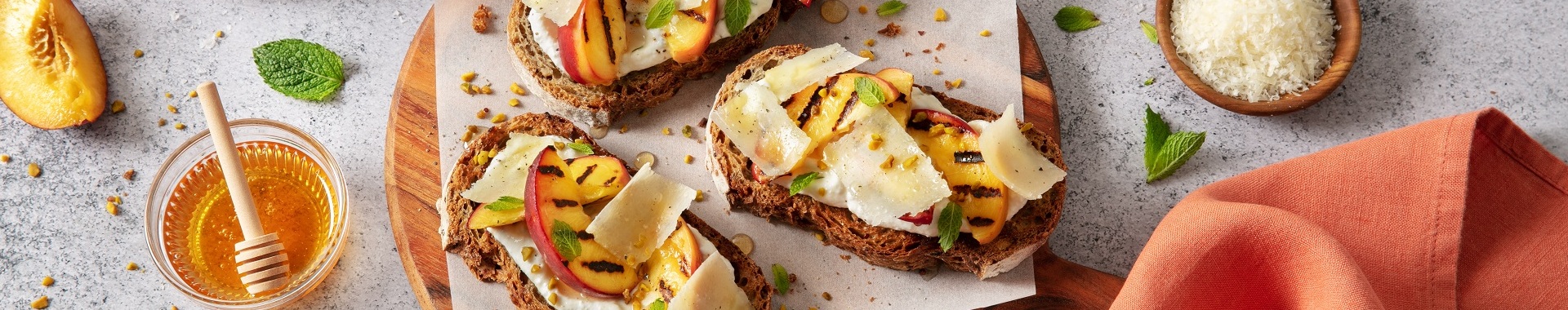 Crostini con crema di ricotta e Grana Padano, pesche grigliate, miele, menta e granella di pistacchi