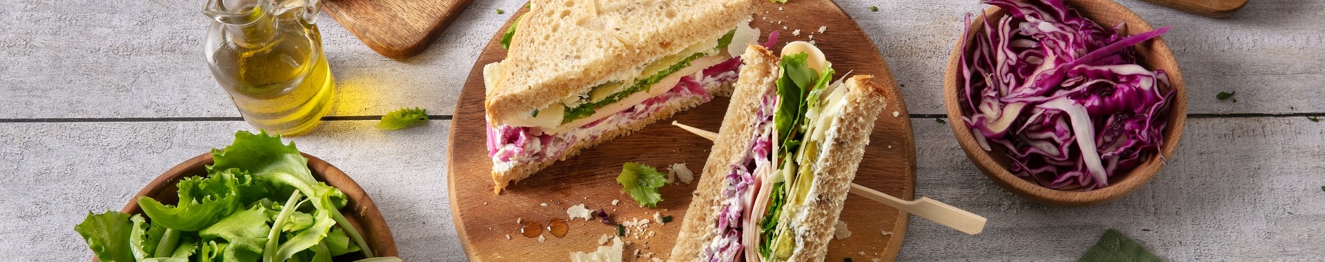 Tramezzini di pane integrale con cavolo viola marinato, crema al Grana Padano con erba cipollina, affettato di tacchino, insalata, cetriolini e scaglie di Grana Padano